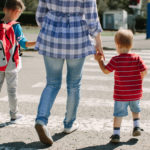 Walking to school. Mother with children crossing a road on way to school.
